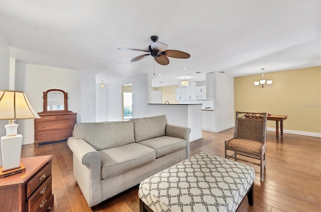 living room with ceiling fan with notable chandelier and wood-type flooring