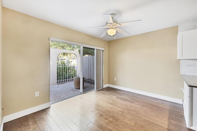 empty room with ceiling fan and light hardwood / wood-style flooring