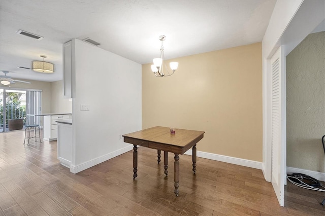 dining space featuring ceiling fan with notable chandelier and light hardwood / wood-style floors