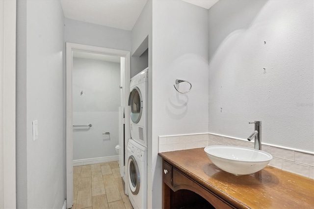 washroom featuring stacked washer and clothes dryer and sink