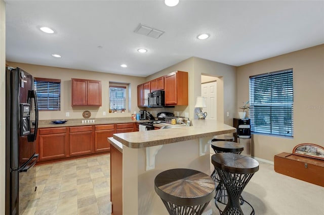 kitchen with kitchen peninsula, a kitchen bar, and black appliances