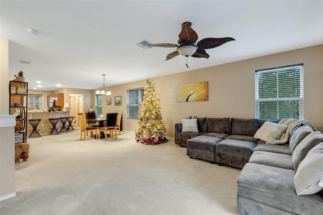 carpeted living room featuring ceiling fan with notable chandelier