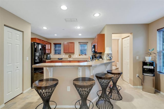 kitchen with kitchen peninsula, a breakfast bar area, and black appliances