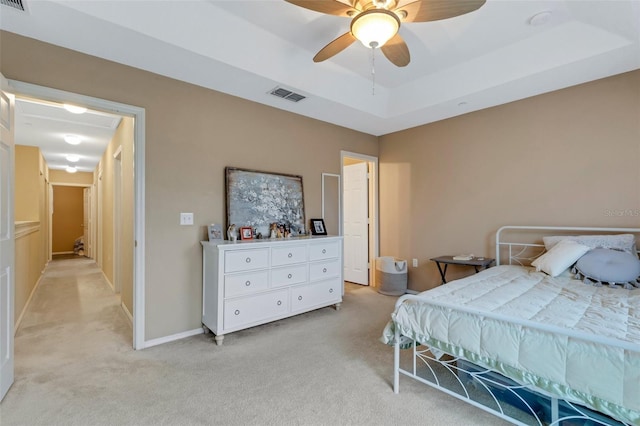 carpeted bedroom with a raised ceiling and ceiling fan