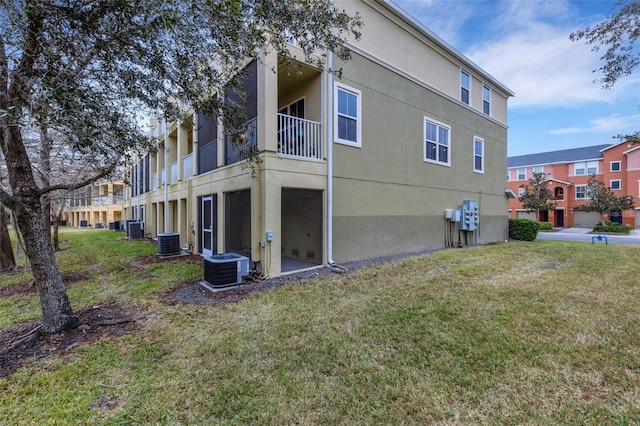 back of property featuring central AC and a lawn