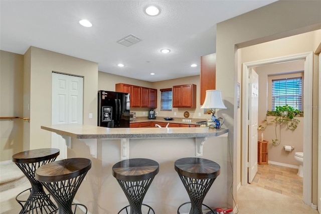 kitchen featuring a breakfast bar area, kitchen peninsula, and black fridge