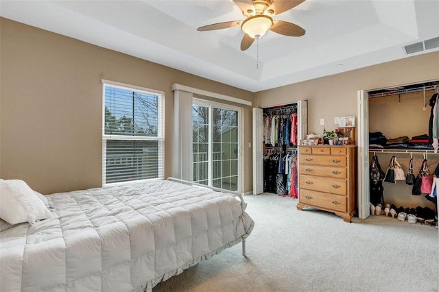 bedroom with multiple closets, carpet, access to exterior, ceiling fan, and a raised ceiling