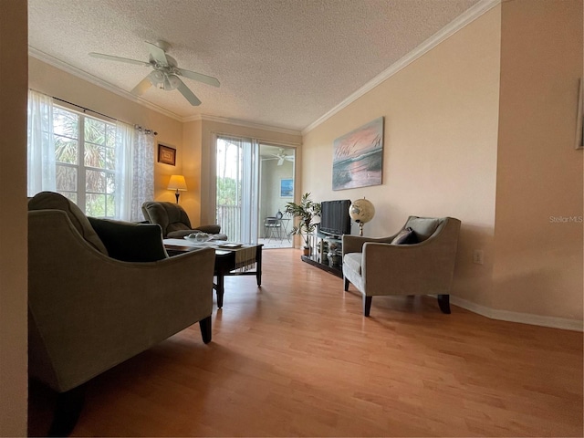 living room with ceiling fan, ornamental molding, a textured ceiling, and light hardwood / wood-style floors