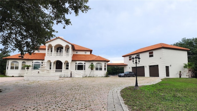 mediterranean / spanish home featuring a front lawn, a garage, and a balcony