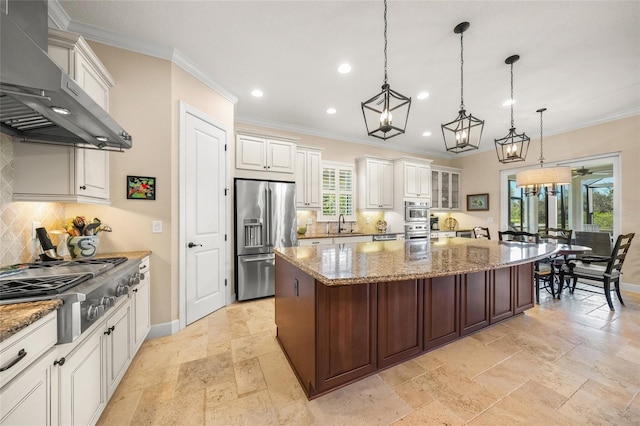 kitchen with white cabinetry, decorative light fixtures, appliances with stainless steel finishes, a large island, and range hood