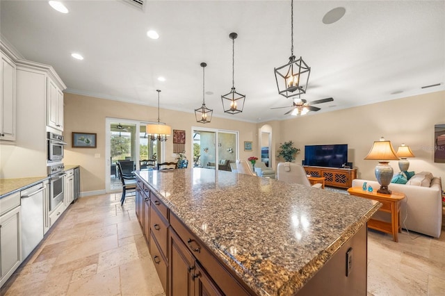 kitchen featuring pendant lighting, ceiling fan, appliances with stainless steel finishes, a center island, and white cabinets