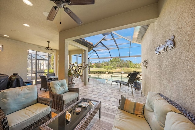 view of patio / terrace featuring an outdoor living space, ceiling fan, and glass enclosure