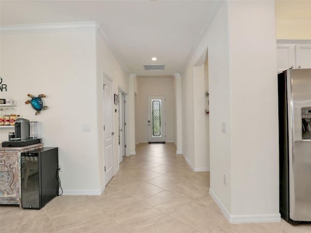 corridor with baseboards, light tile patterned flooring, visible vents, and crown molding