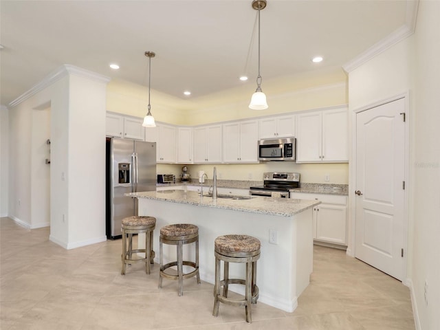 kitchen with a kitchen island with sink, stainless steel appliances, a sink, white cabinets, and ornamental molding