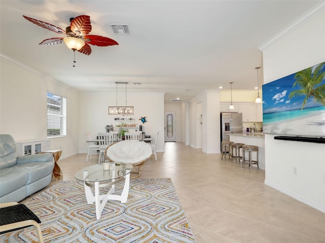 living room with ceiling fan, light tile patterned flooring, visible vents, baseboards, and crown molding