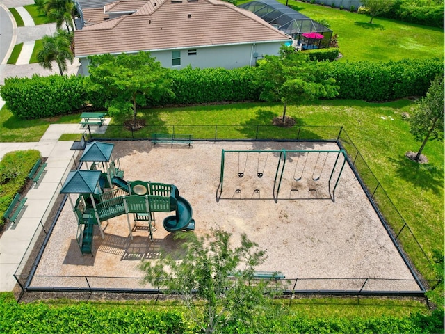 view of property's community featuring playground community, fence, and a lawn