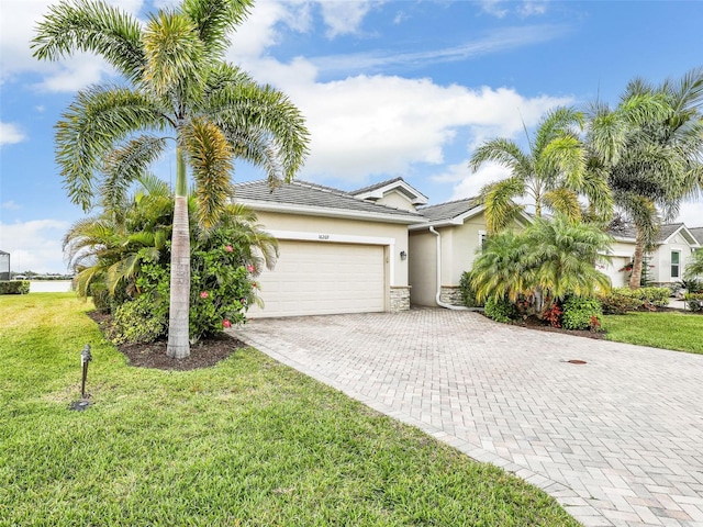 view of front of house featuring an attached garage, a front lawn, decorative driveway, and stucco siding