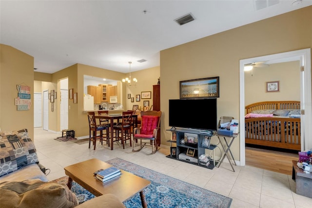 tiled living room with ceiling fan with notable chandelier