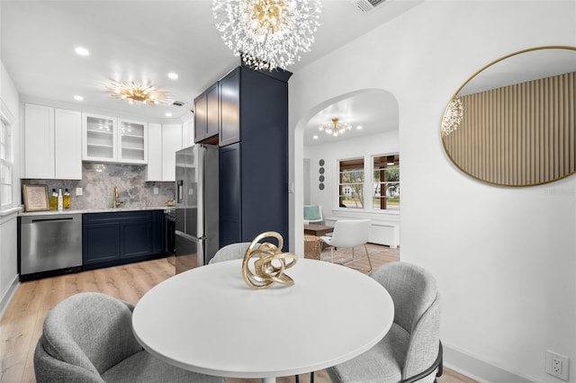 dining area with light wood-type flooring, a chandelier, and sink