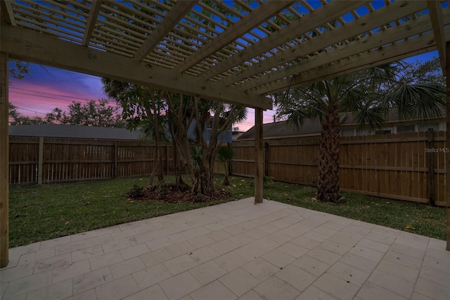 patio terrace at dusk featuring a yard and a pergola