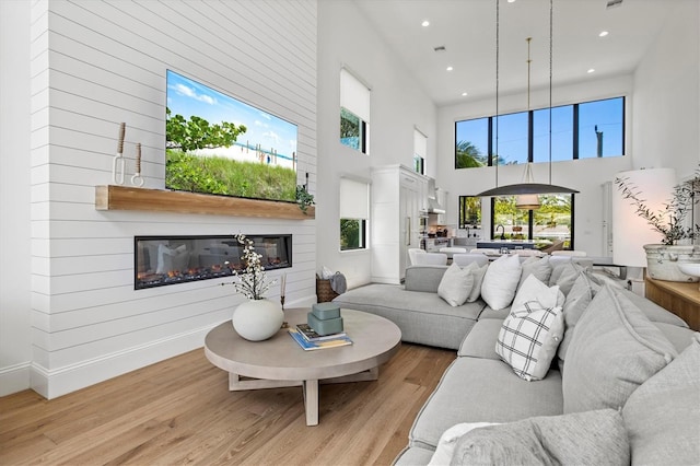 living room featuring a towering ceiling and light wood-type flooring