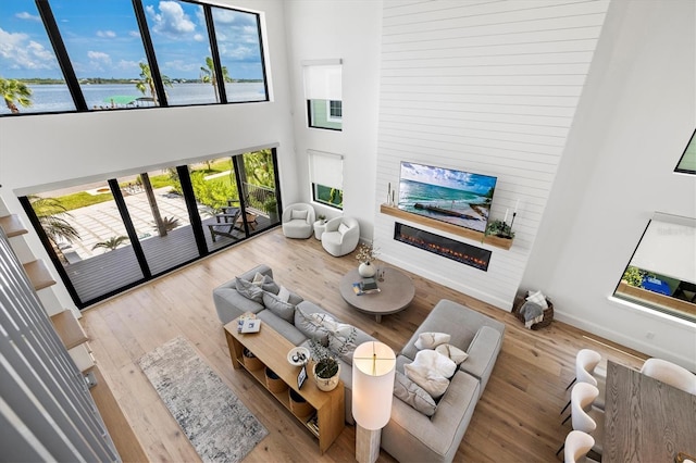 living room featuring a high ceiling, wood-type flooring, and a water view