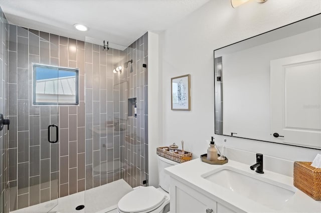 bathroom featuring a shower with door, vanity, and toilet