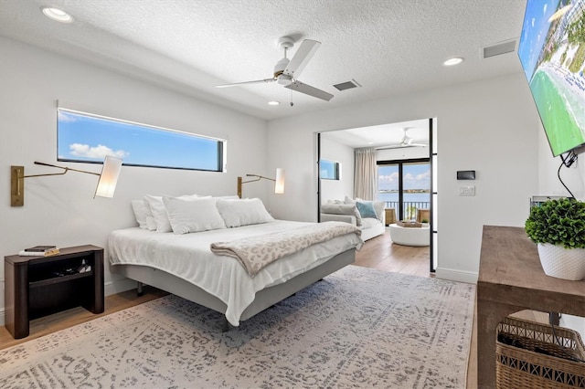 bedroom featuring ceiling fan, access to outside, hardwood / wood-style floors, and a textured ceiling