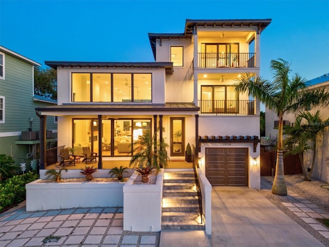 rear view of property featuring a balcony and a garage