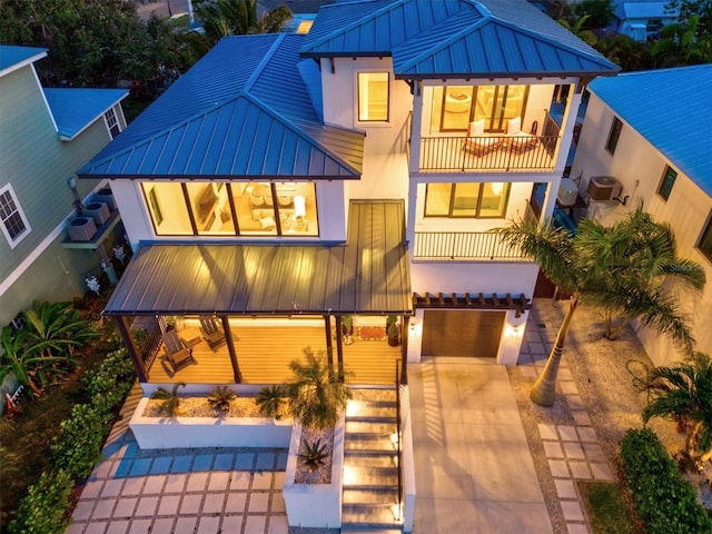 rear view of house featuring a garage, a balcony, and central air condition unit