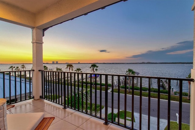 balcony at dusk featuring a water view