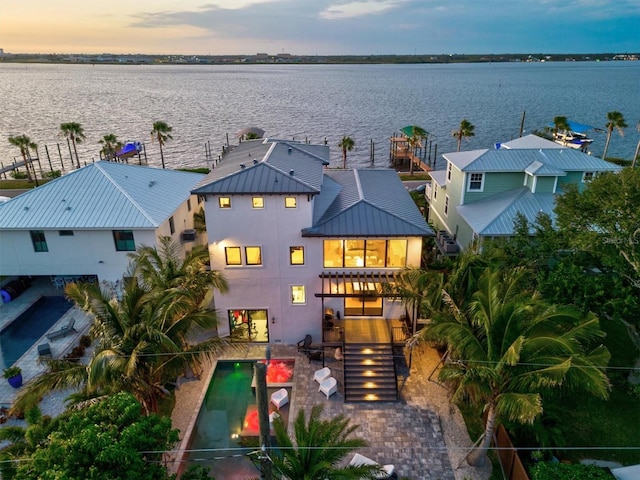 back house at dusk with a patio and a water view