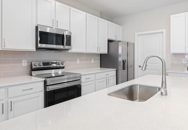 kitchen with sink, backsplash, white cabinets, and stainless steel appliances