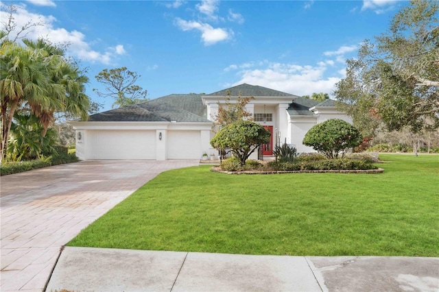 view of front of property featuring an attached garage, a front lawn, decorative driveway, and stucco siding