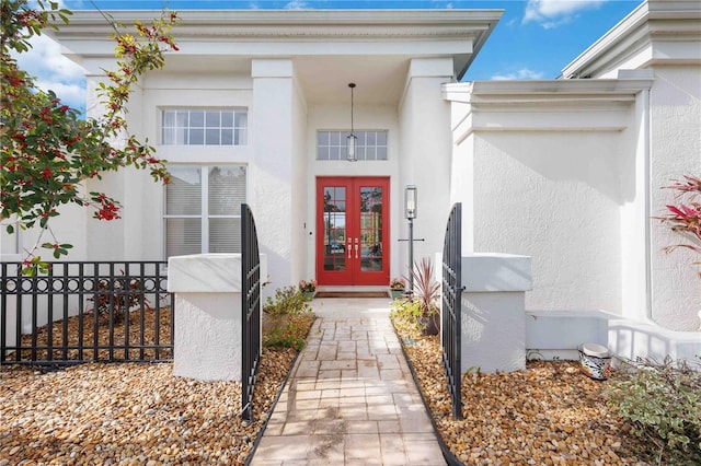 doorway to property with stucco siding, fence, and french doors