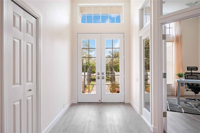 doorway to outside featuring french doors, wood finished floors, a high ceiling, and baseboards