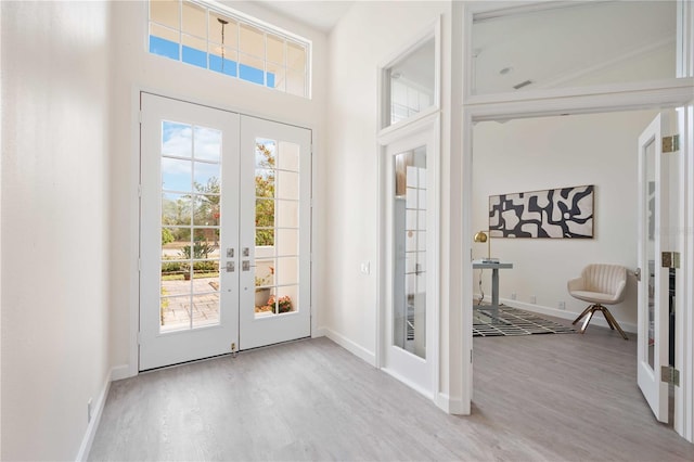 entryway with a high ceiling, baseboards, wood finished floors, and french doors