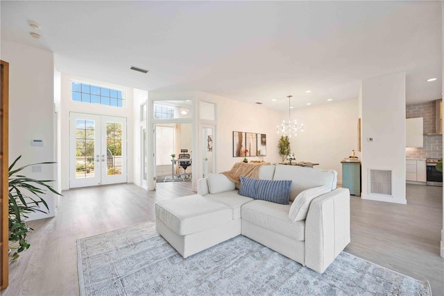 living room featuring an inviting chandelier, visible vents, wood finished floors, and french doors