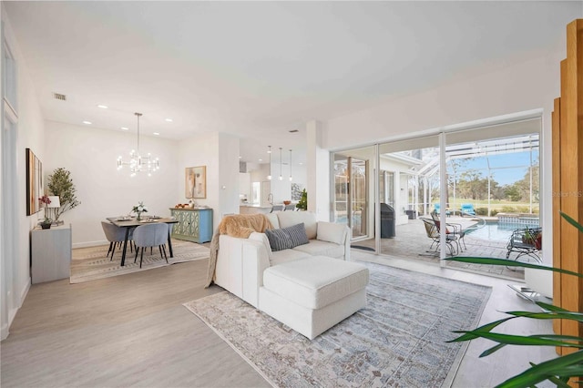 living room with visible vents, a sunroom, light wood-style flooring, an inviting chandelier, and recessed lighting