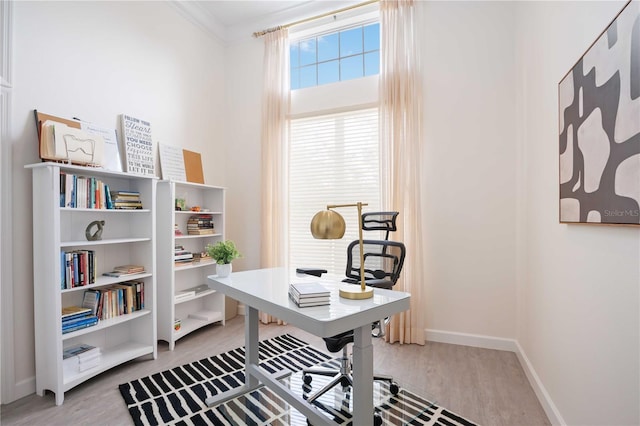 home office with wood-type flooring and ornamental molding