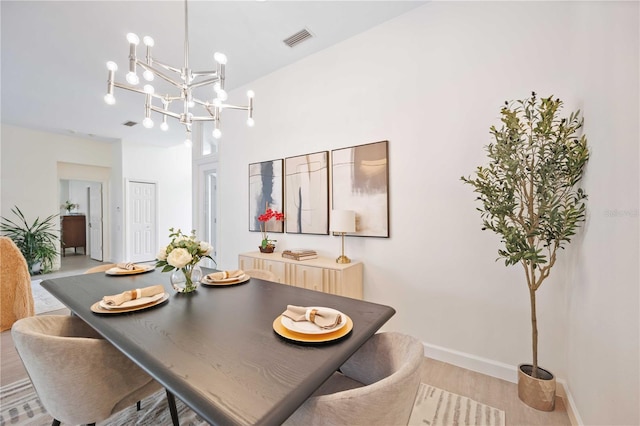 dining area featuring a chandelier, visible vents, light wood-style flooring, and baseboards