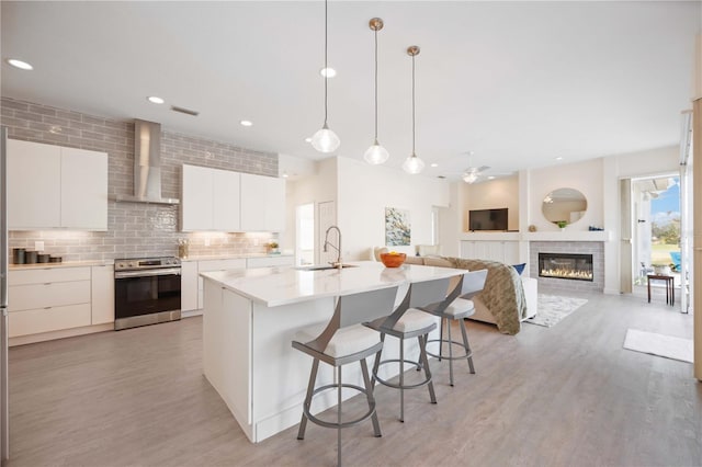 kitchen featuring a sink, electric stove, wall chimney range hood, tasteful backsplash, and modern cabinets