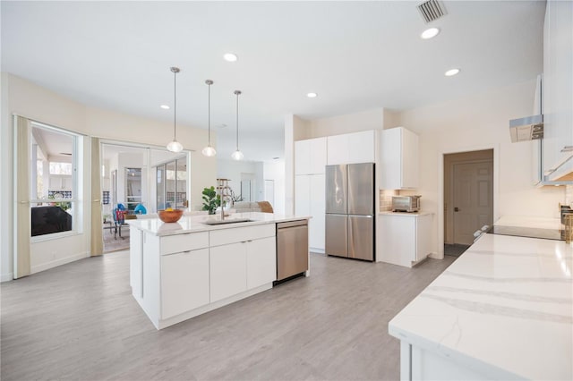 kitchen with visible vents, appliances with stainless steel finishes, a kitchen island with sink, a sink, and light wood-type flooring