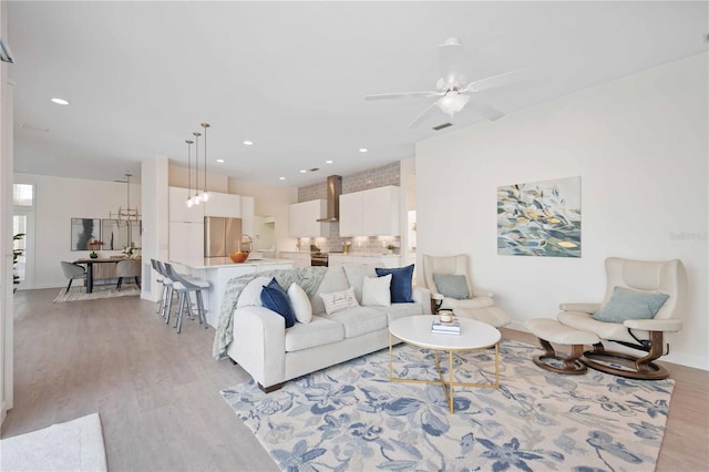 living area with a ceiling fan, recessed lighting, light wood-style flooring, and baseboards