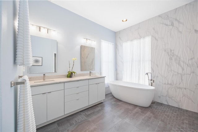 bathroom with vanity, a bath, and tile walls