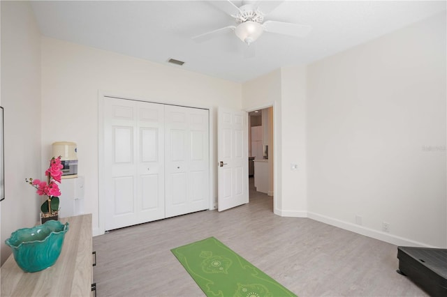 unfurnished bedroom featuring ceiling fan, a closet, and light wood-type flooring