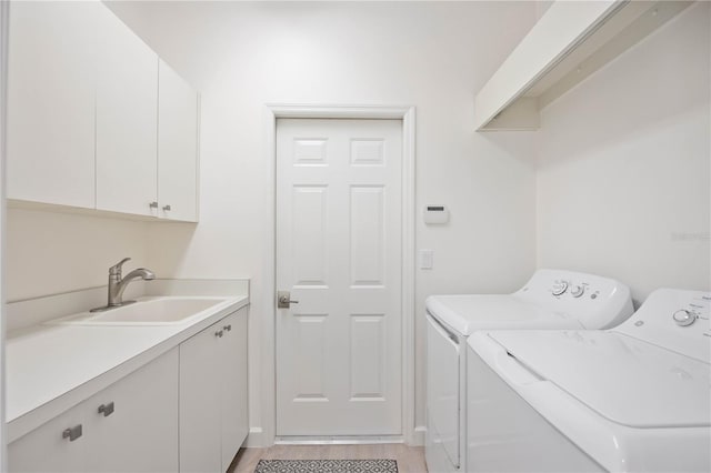 clothes washing area featuring washing machine and dryer, cabinet space, a sink, and light wood-style flooring