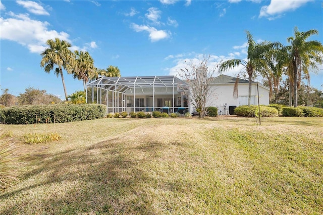 back of property with a lawn and glass enclosure