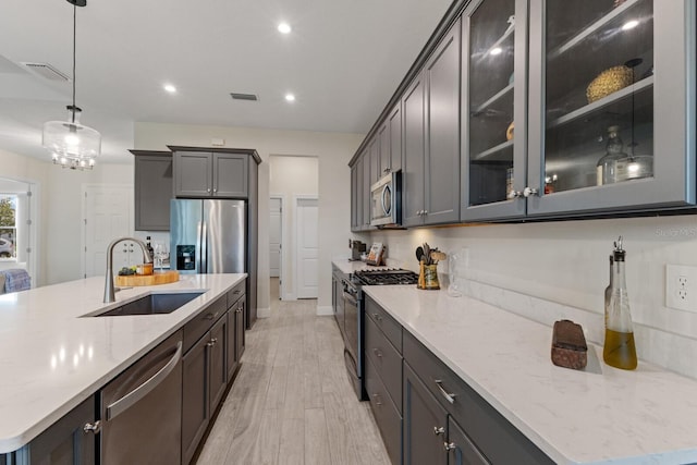 kitchen with hanging light fixtures, an island with sink, sink, and stainless steel appliances