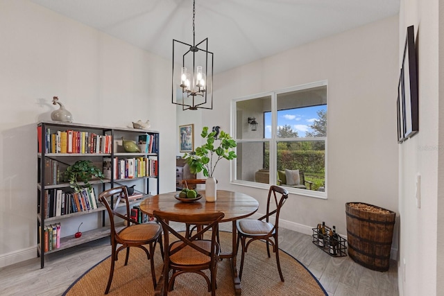 dining space with light hardwood / wood-style floors and a notable chandelier